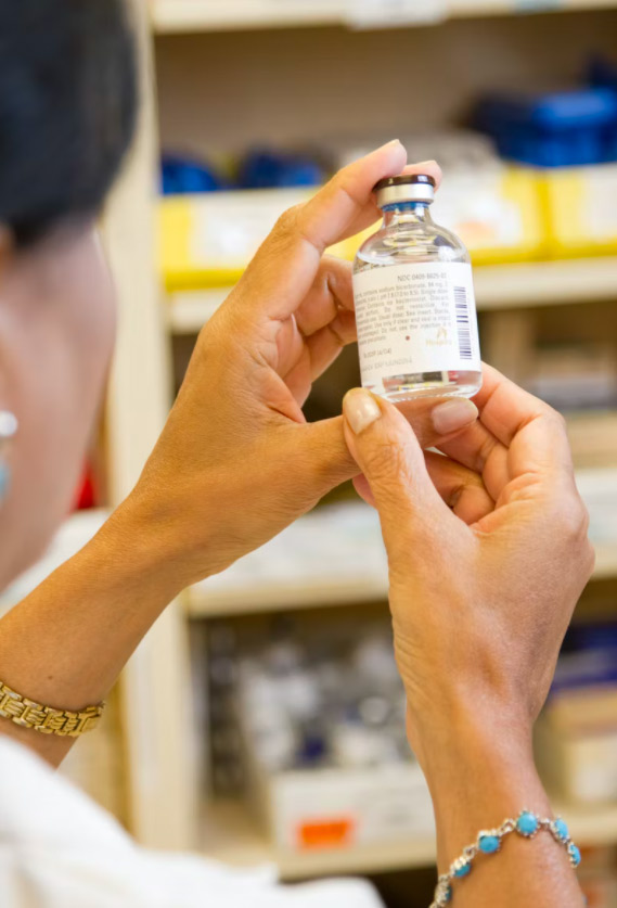 a woman holds a bottle of prescription serum produced by a top business in the pharmaceutical industry